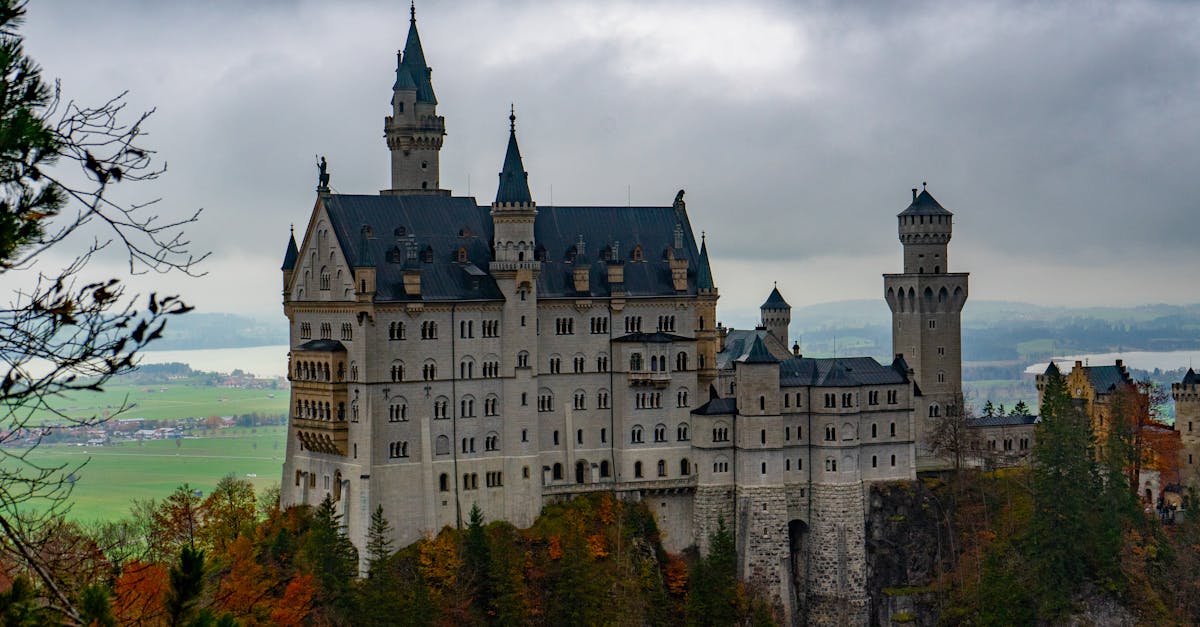 Dramatic view of Neuschwanstein Castle amidst colorful autumn foliage in Bavaria, Germany.