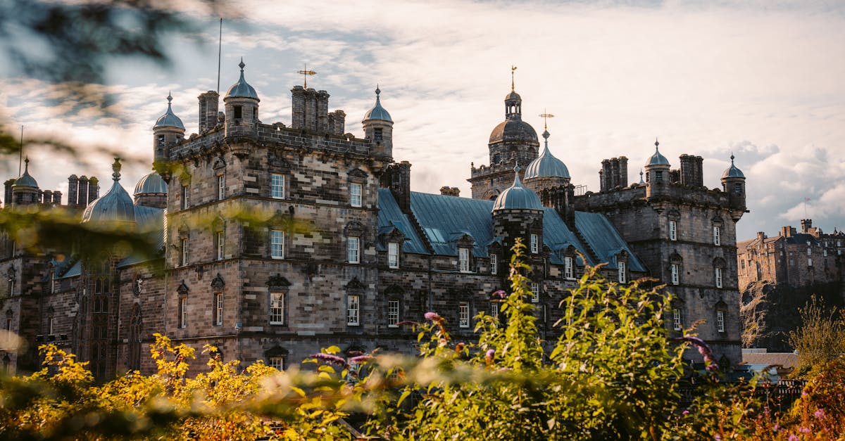 Charming view of Edinburgh Castle surrounded by autumn foliage, under a bright sky.