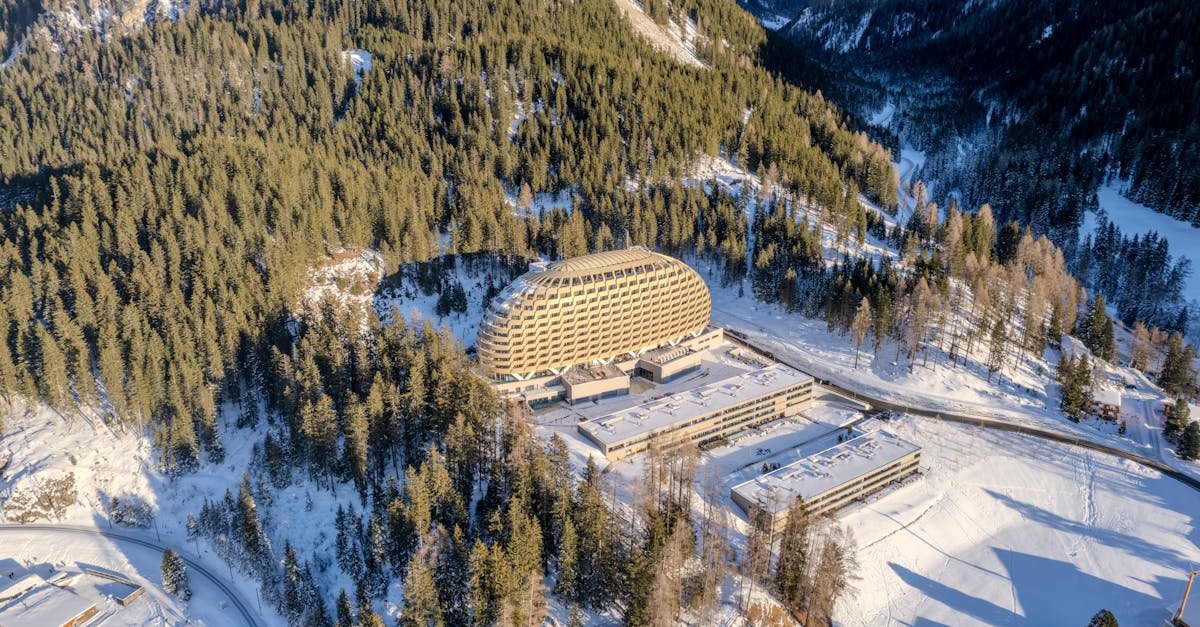 Stunning aerial view of a modern hotel surrounded by snowy forests in the Swiss Alps, Davos.