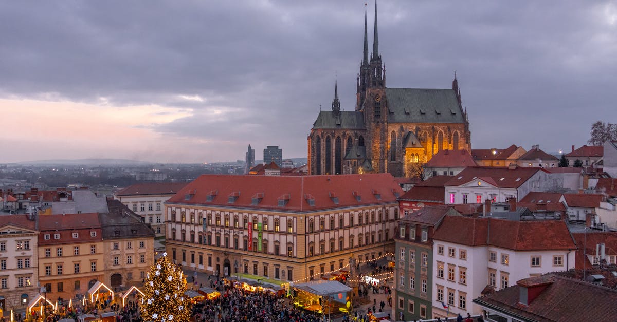 Aerial shot of Brno's illuminated cathedral and Christmas market at dusk.
