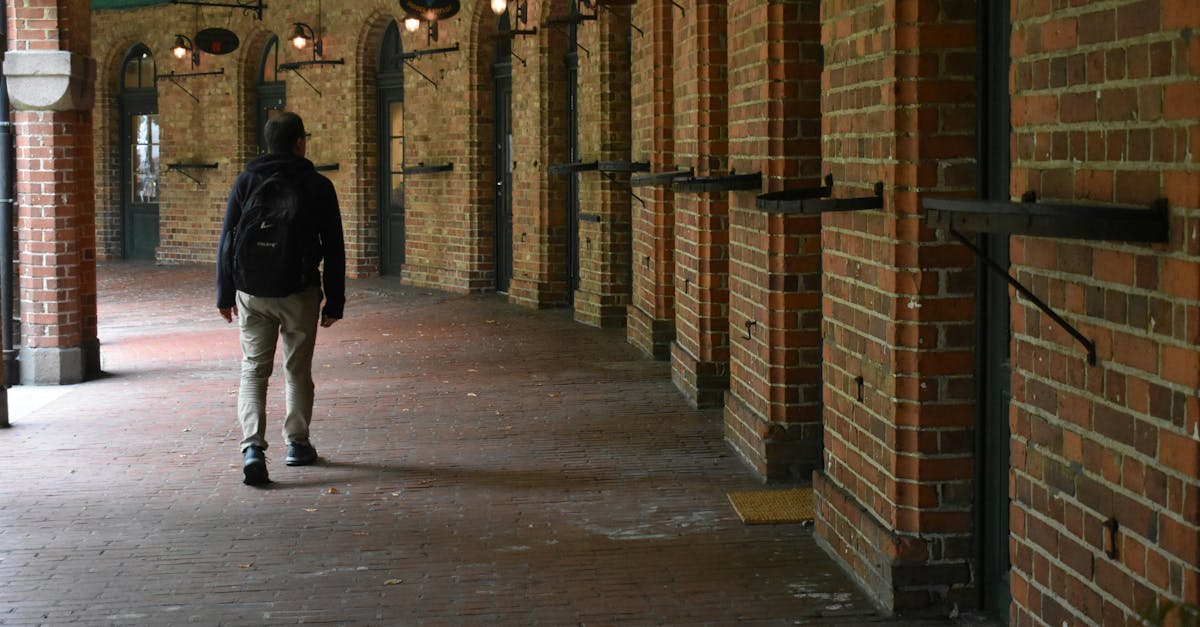 Man with backpack walking through a historic brick corridor.