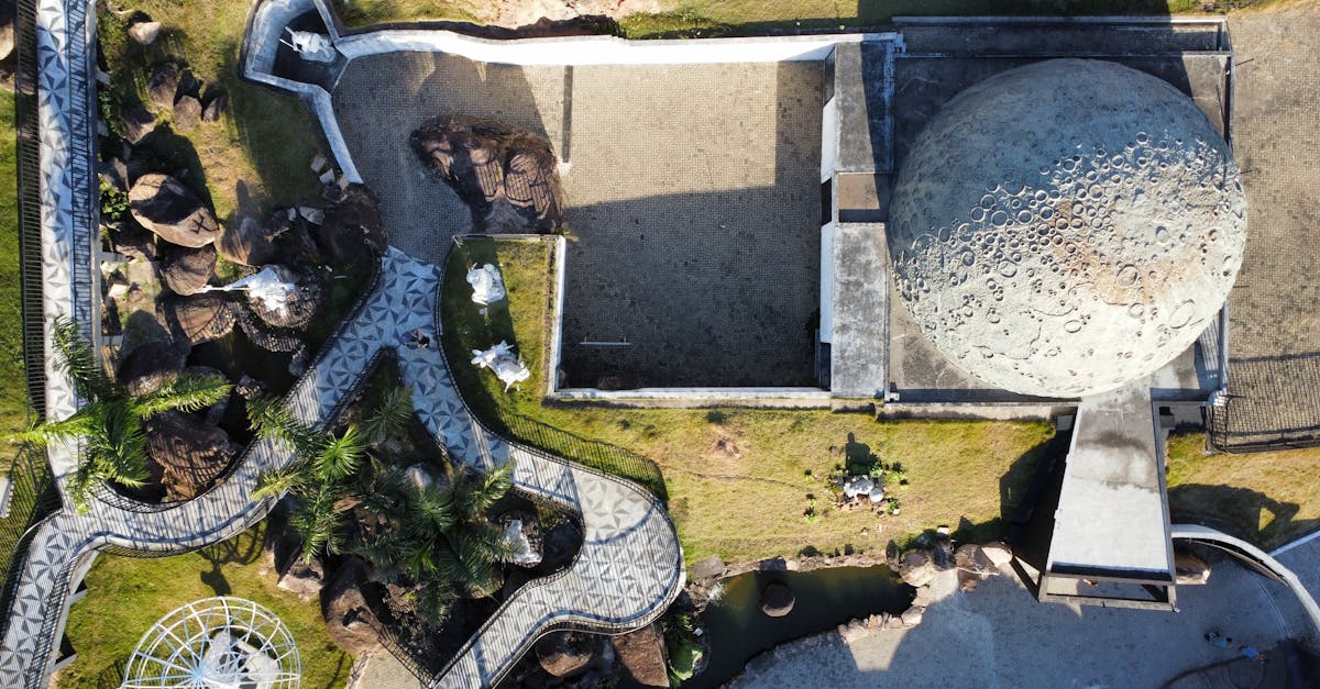 Aerial shot of geometric park pathways and dome structure, casting shadows.