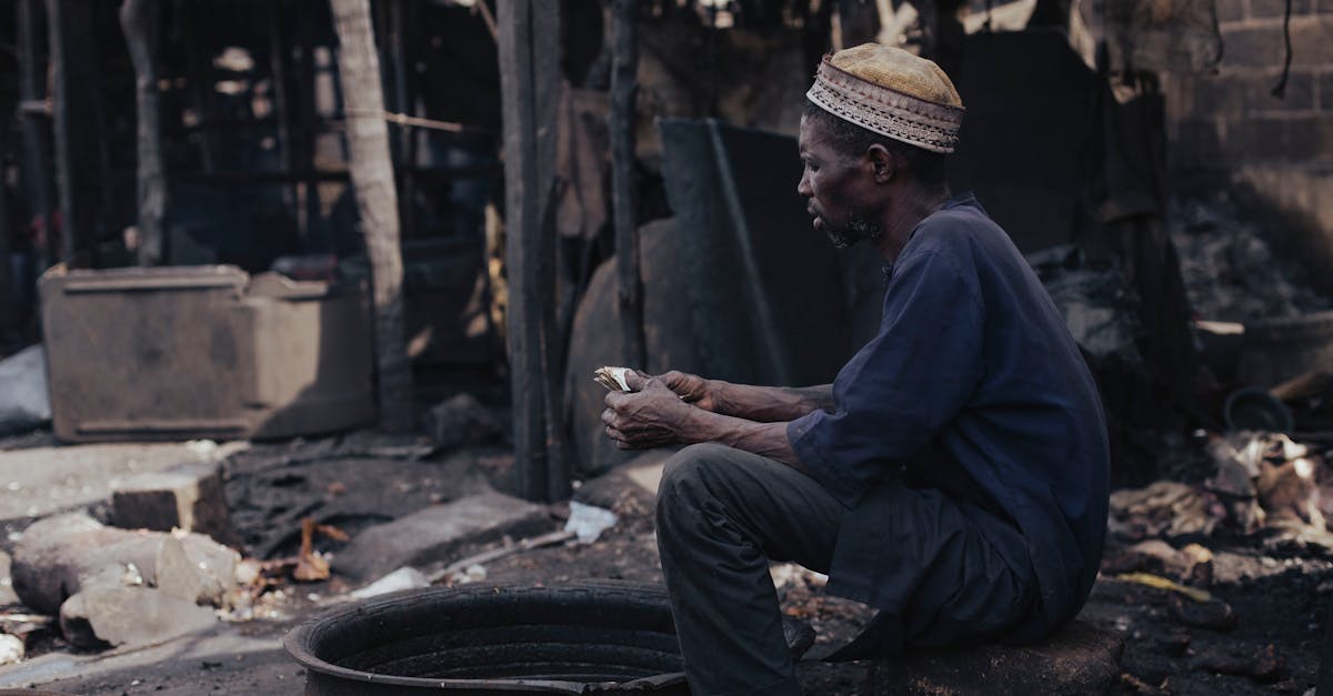 Elderly man in outdoor rustic setting examining an item, conveying contemplation and solitude.