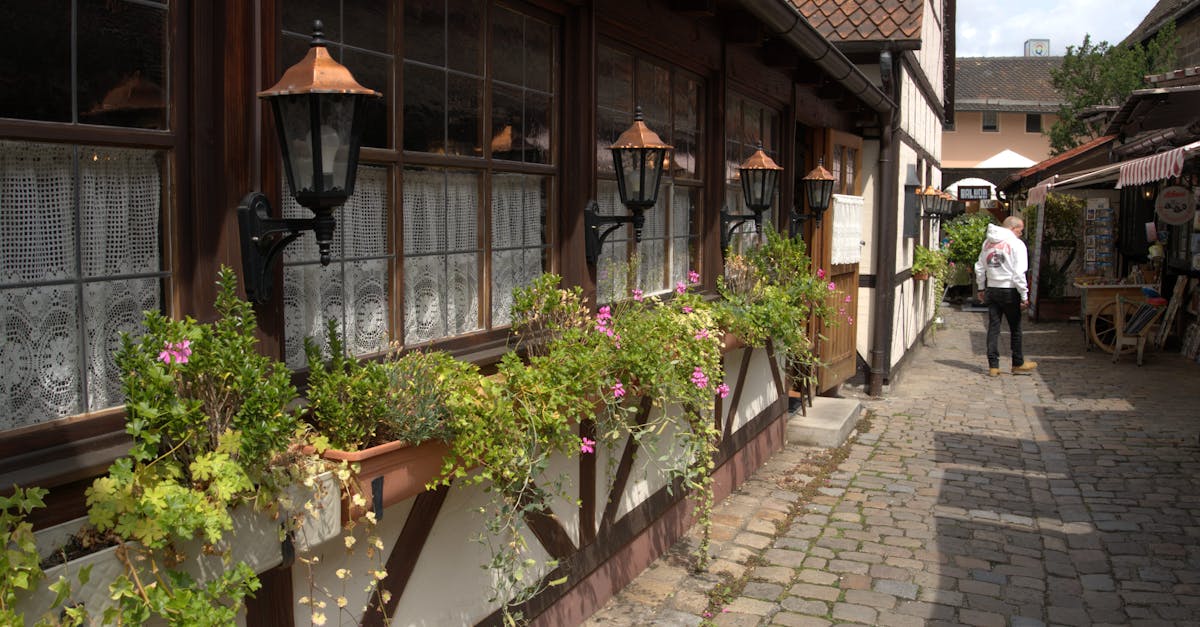 Quaint cobblestone alley bordered by picturesque vintage buildings and floral arrangements.