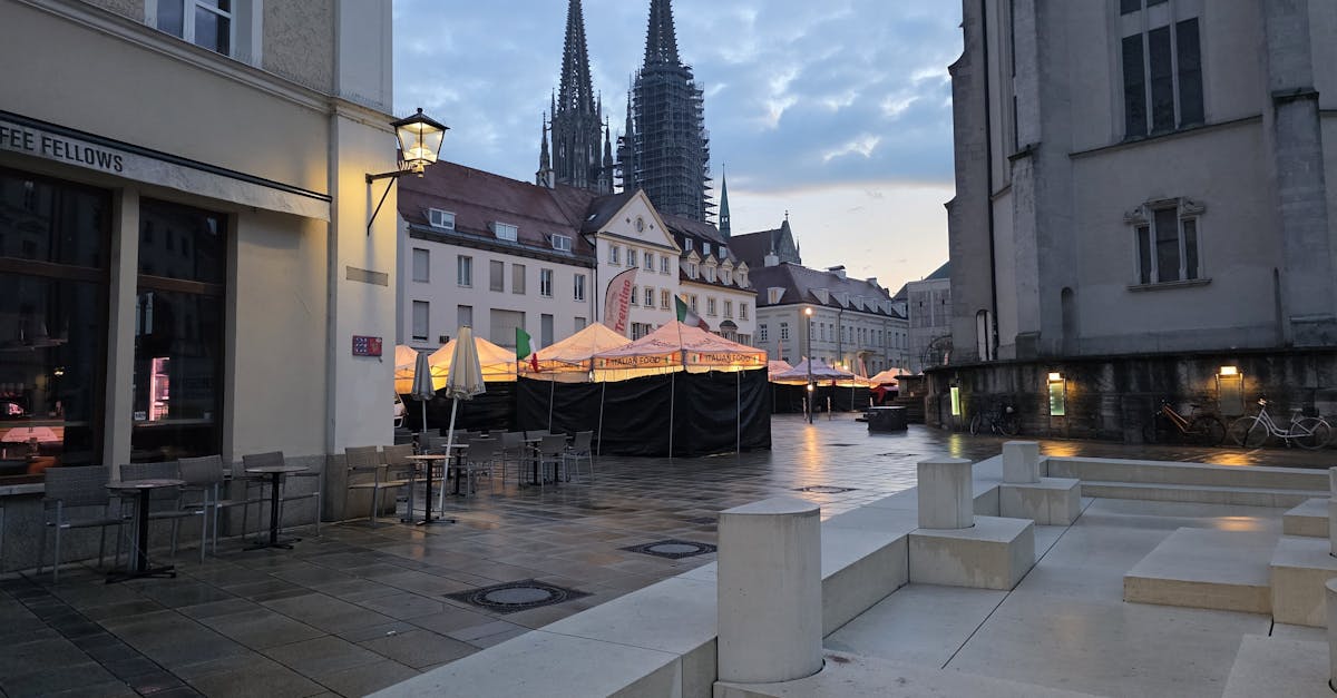 Twilight view of Regensburg Cathedral, Germany with street architecture and empty outdoor seating.