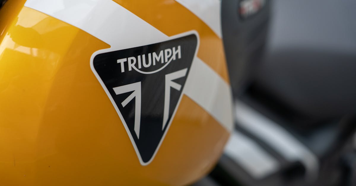 Detailed view of a yellow Triumph motorcycle fuel tank showcasing its logo.