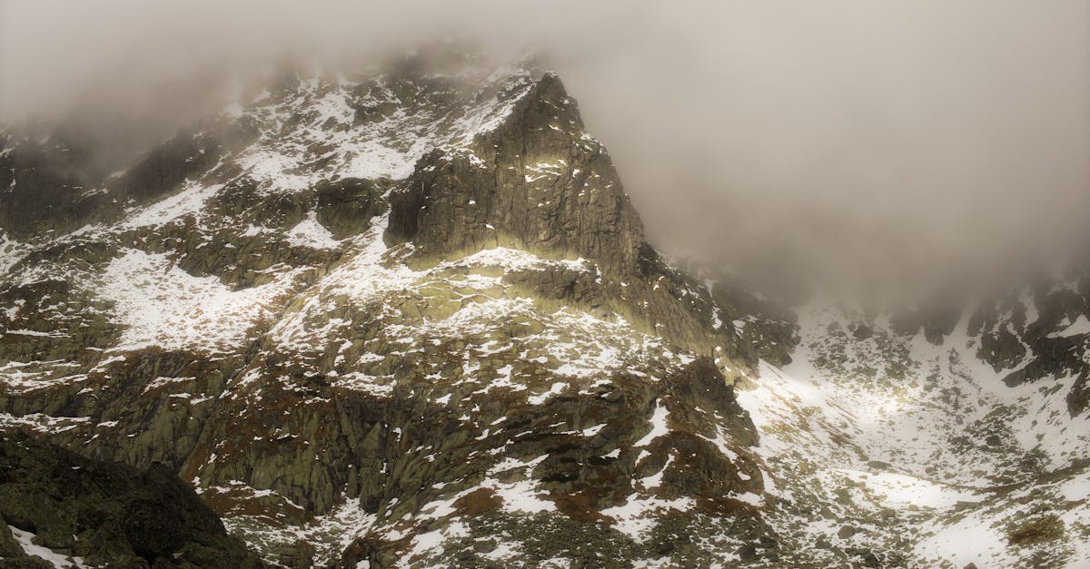 Breathtaking view of Slovakia's Tatra Mountains with mist-covered peaks and light snow.