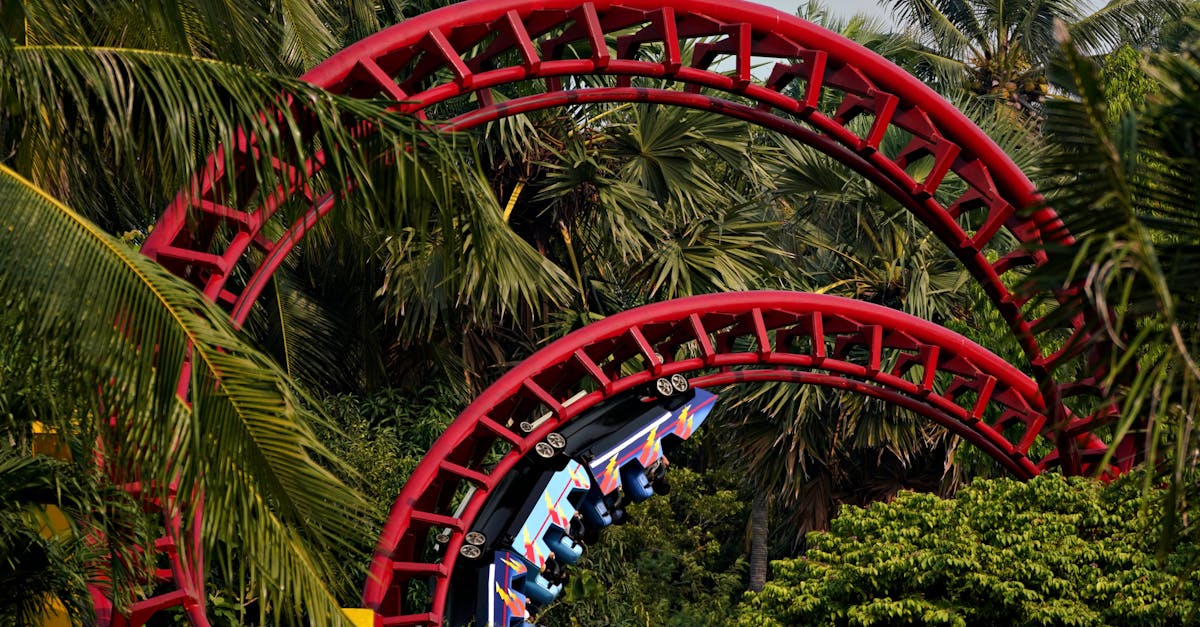 Colorful roller coaster loops through lush palm trees on a sunny day.