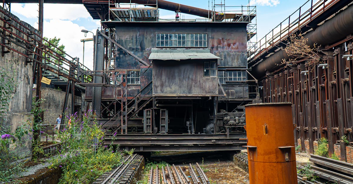 A rusty, abandoned factory with structural decay and overgrown vegetation.
