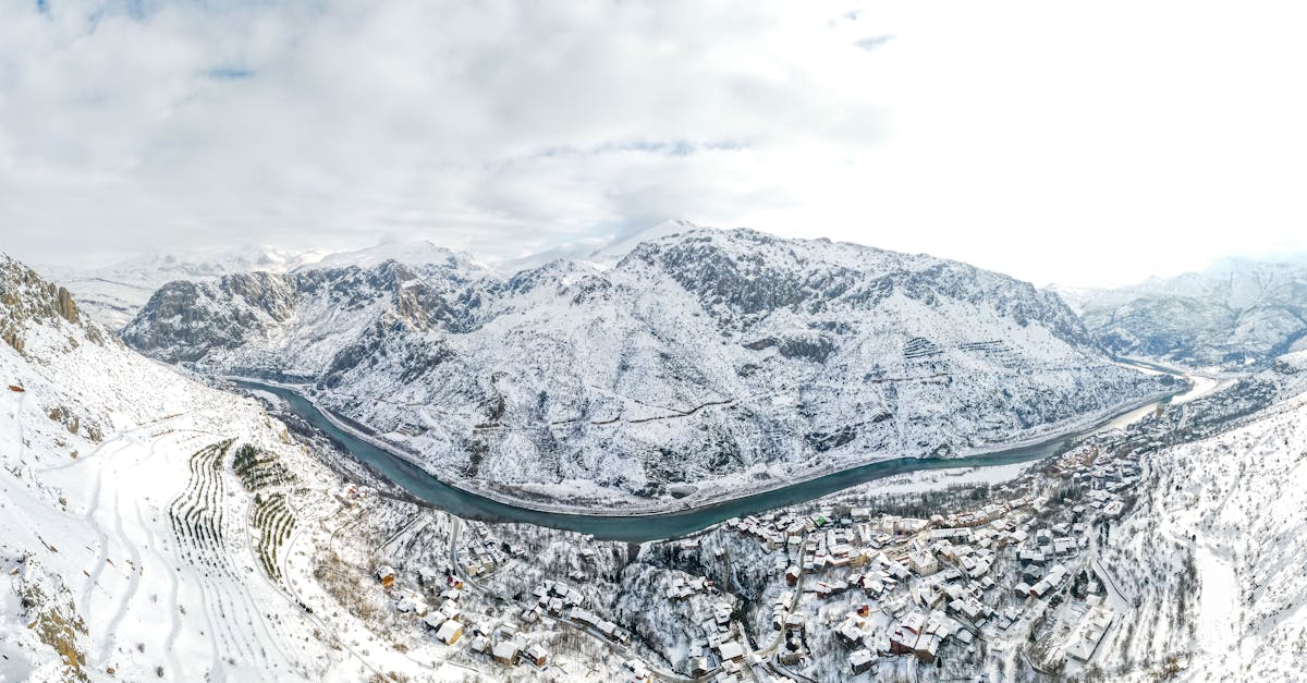 Breathtaking aerial view of a snowy village nestled among majestic mountains and a winding river.