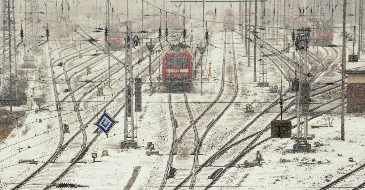 A red train on snow-covered railway tracks during a snowy winter day.