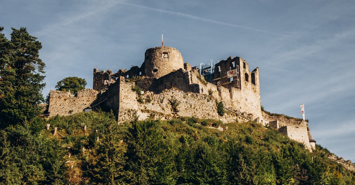 A majestic view of the ancient castle ruins atop a lush hill under a clear sky.