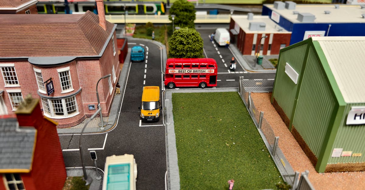 Intricate model railway scene featuring a classic red double-decker bus and surrounding miniature architecture.
