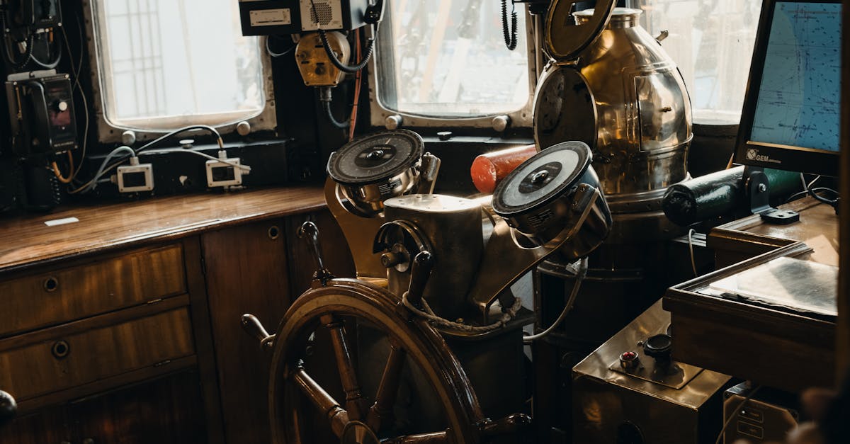 A detailed view of a vintage ship's steering wheel and navigational instruments inside a nautical cabin.