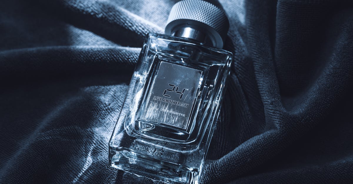 Glass perfume bottle with elegant design resting on a dark textured fabric, showcasing luxury and sophistication.