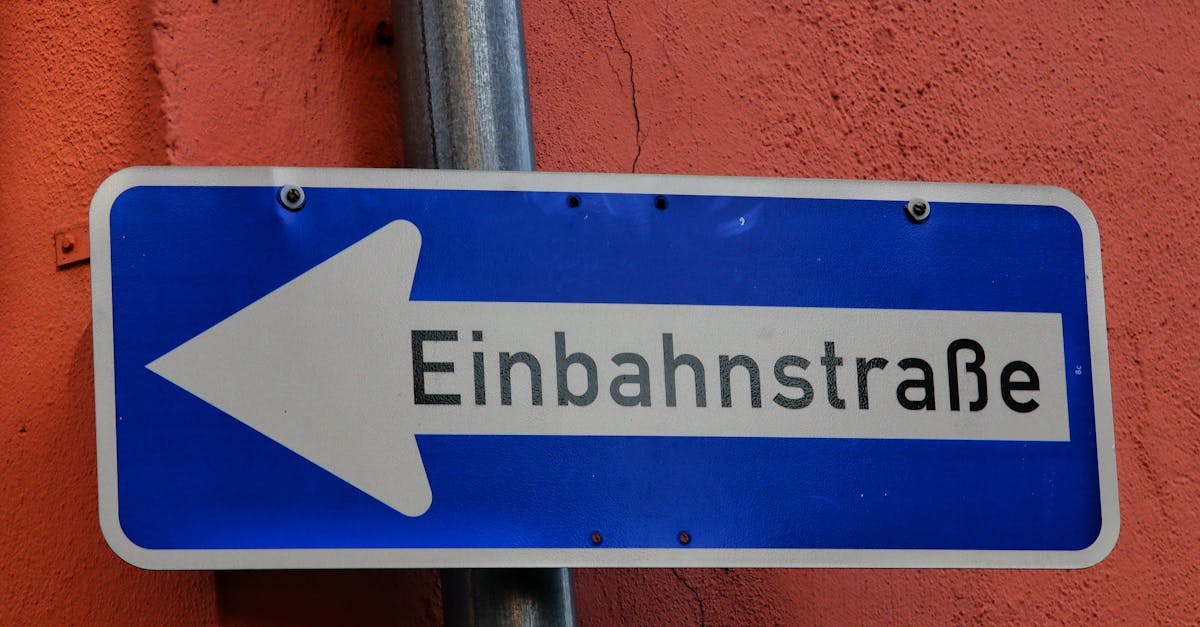 Blue one-way street sign with arrow labeled 'Einbahnstraße' against an orange wall.