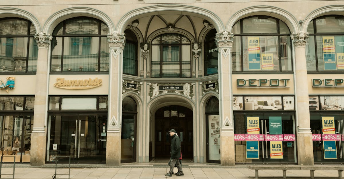 A city scene showing a historic European building with shops and a pedestrian.