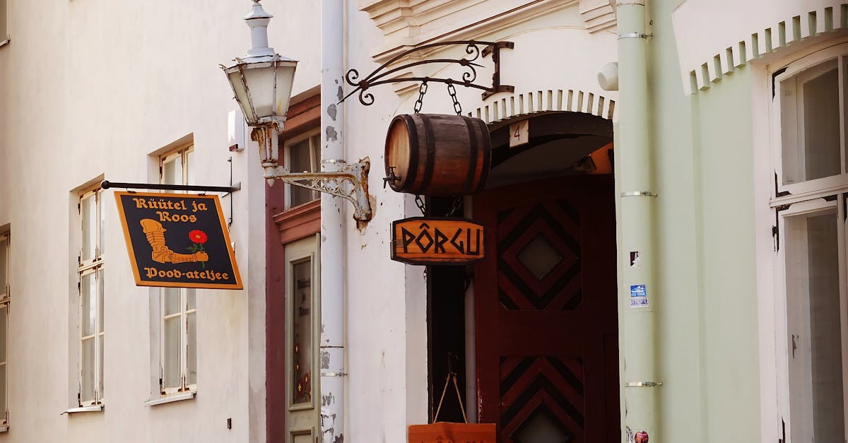 Rustic shop signs hanging on a historic building facade in Tallinn's Old Town.
