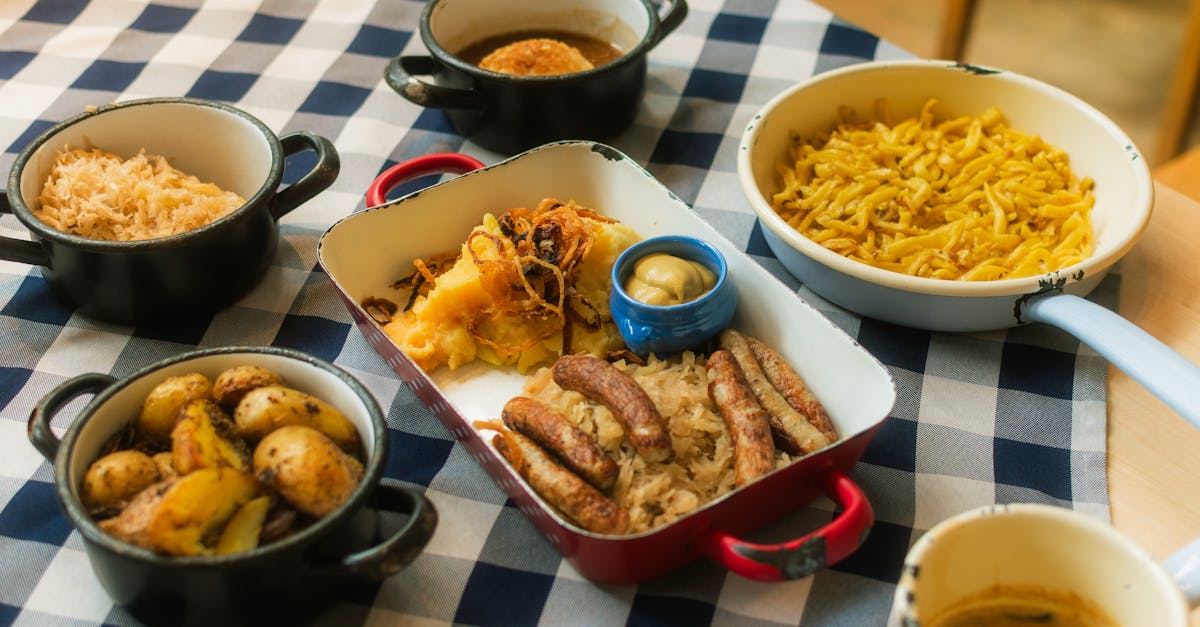 A delicious assortment of German cuisine featuring sausages, potatoes, sauerkraut, and more on a checkered tablecloth.