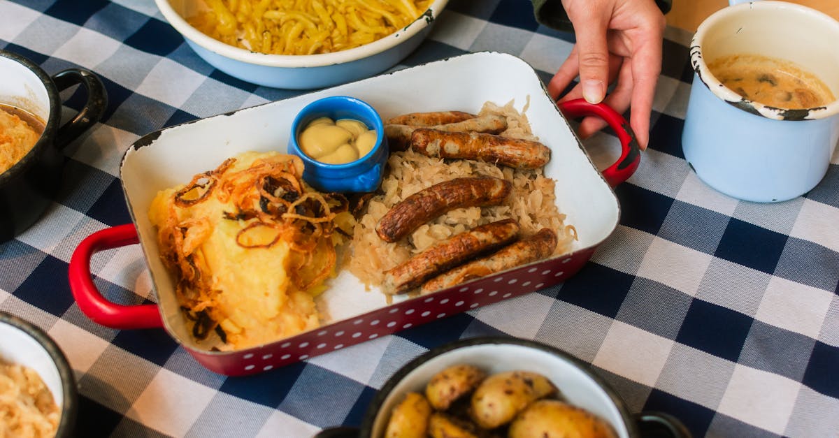 A homestyle Bavarian meal featuring sausages, potatoes, and sauerkraut on a checkered tablecloth.