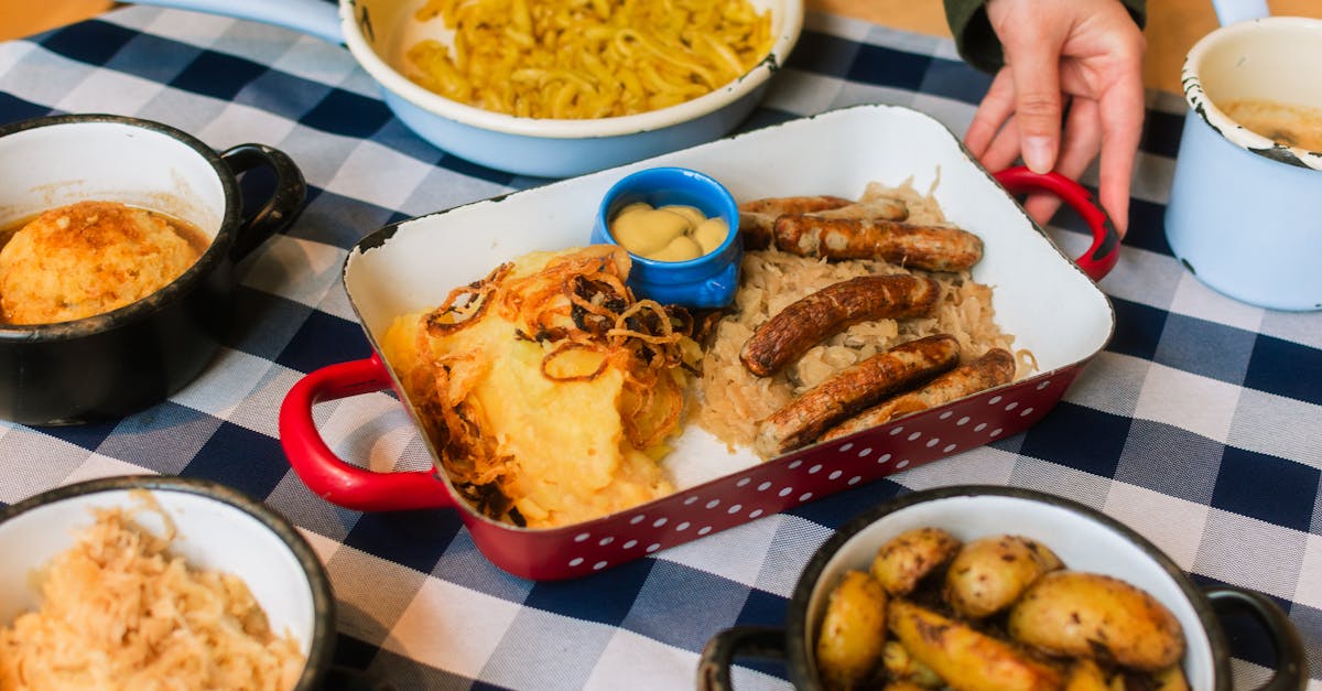 A hearty German meal featuring sausages, potatoes, and sauerkraut on a checkered tablecloth.