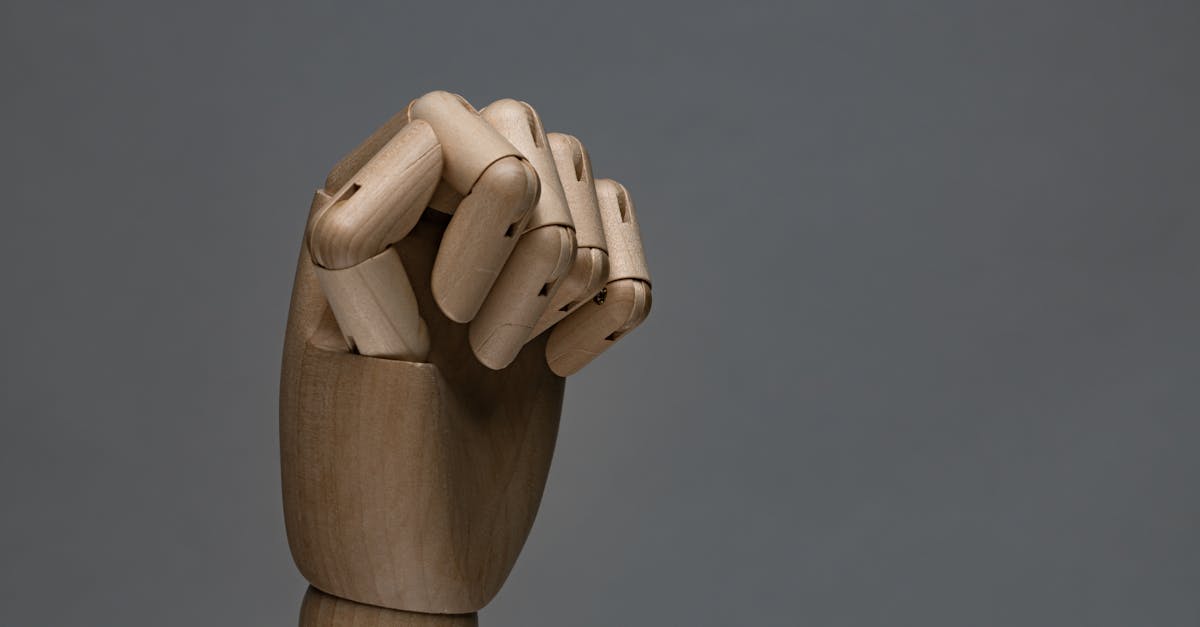 Detailed wooden mannequin hand showing a fist with a gray backdrop.