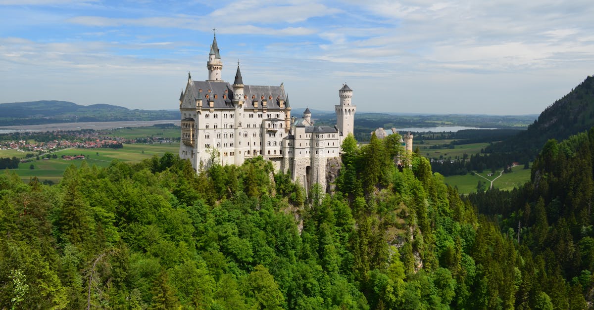 Capture of iconic Neuschwanstein Castle surrounded by vibrant green forest in Bavarian landscape.