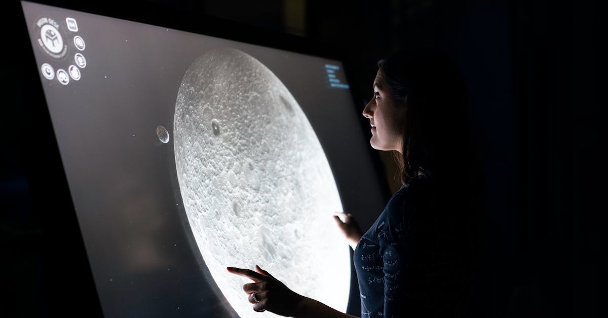 A woman interacts with a touchscreen showing the moon's surface, exploring lunar details.