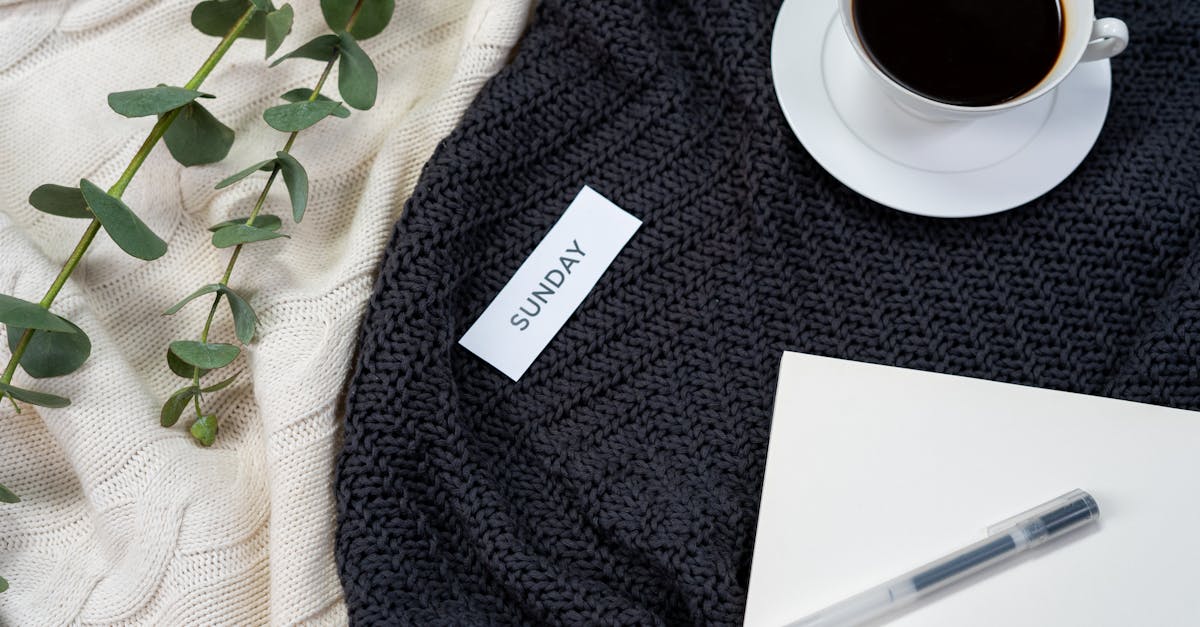 A flat lay of coffee, a knitted blanket, and a notepad creates a cozy Sunday atmosphere.