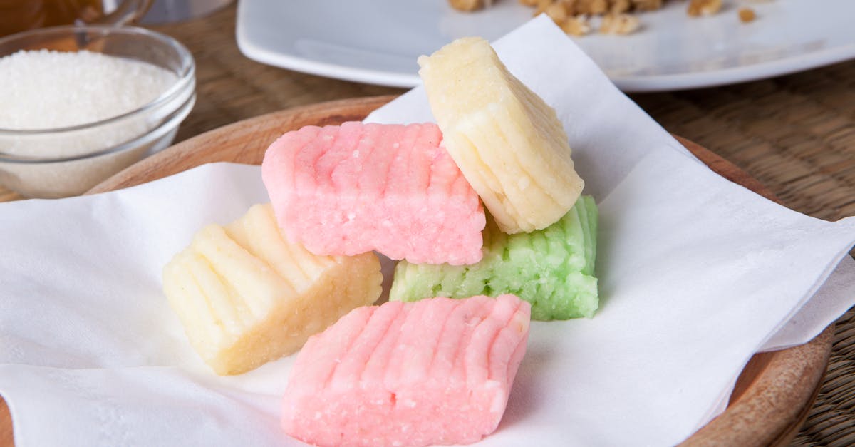 A close-up of colorful Getuk Lindri, a traditional Indonesian cassava snack served on a wooden plate.