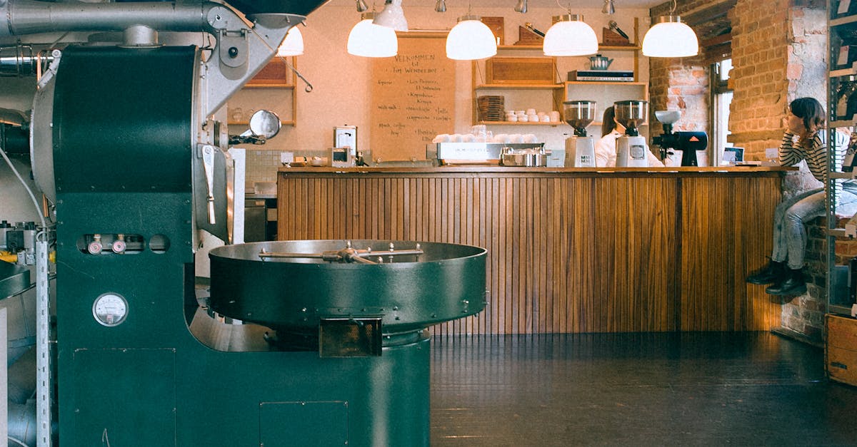 Coffee roasting equipment in cafeteria with lamps and crop unrecognizable female bartender with partner at work