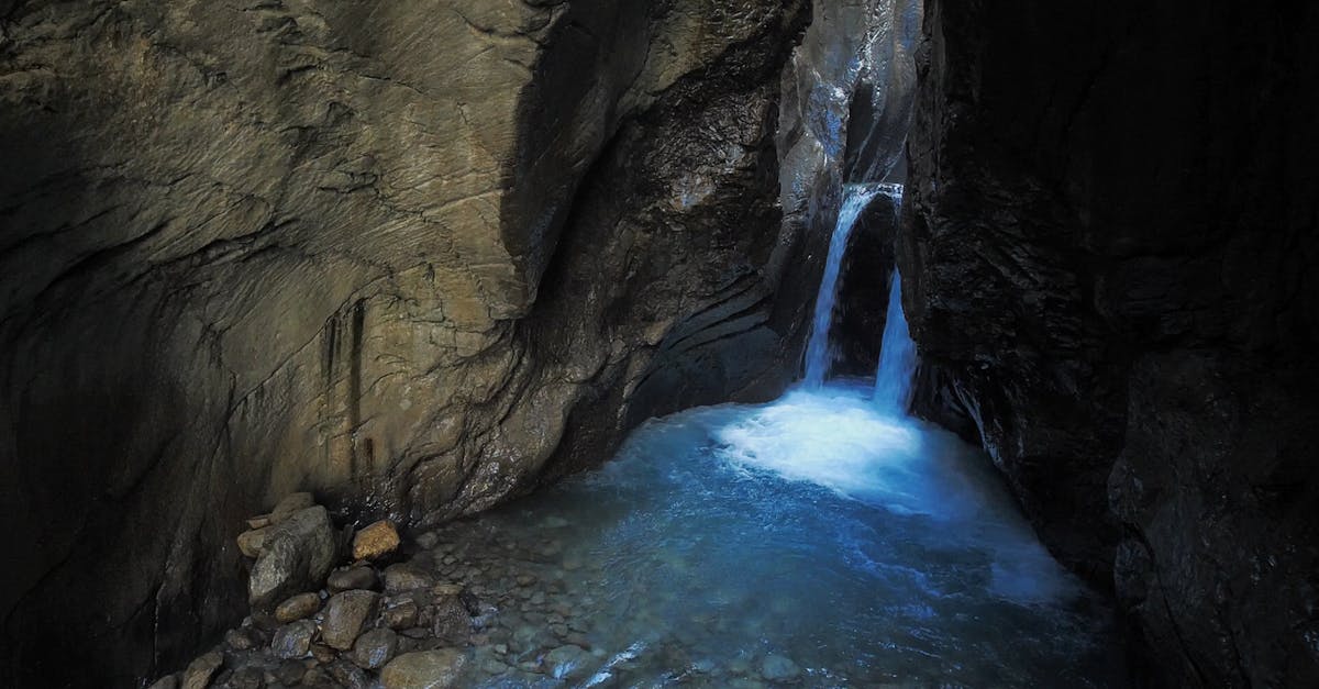 Discover tranquility with a secluded waterfall flowing through a rocky cave setting.