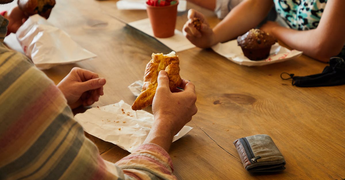 Group of people enjoying pastries together at a wooden table in a casual setting.