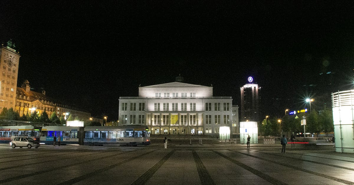 A nighttime view of the illuminated Leipzig Opera House with surrounding cityscape.