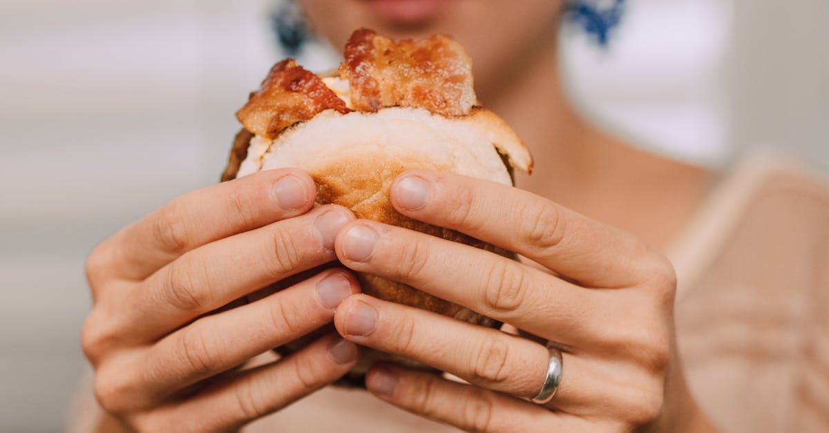 A close-up image of a person holding a delicious bacon sandwich, ready to enjoy.