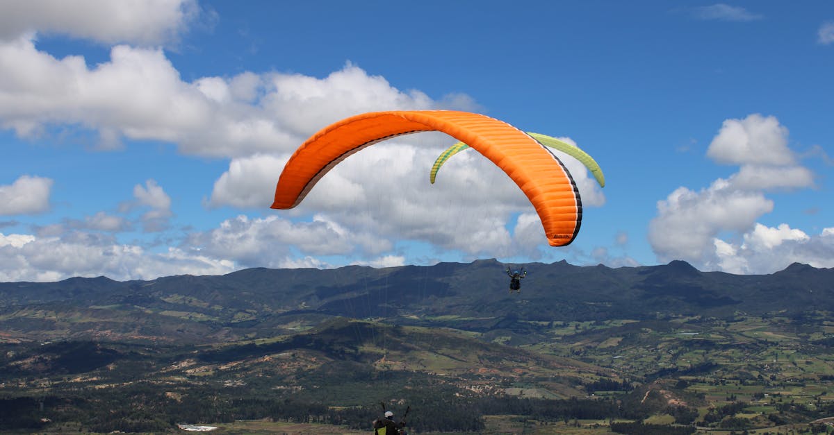 Experience the thrill of paragliding over a breathtaking mountain vista under a clear blue sky.