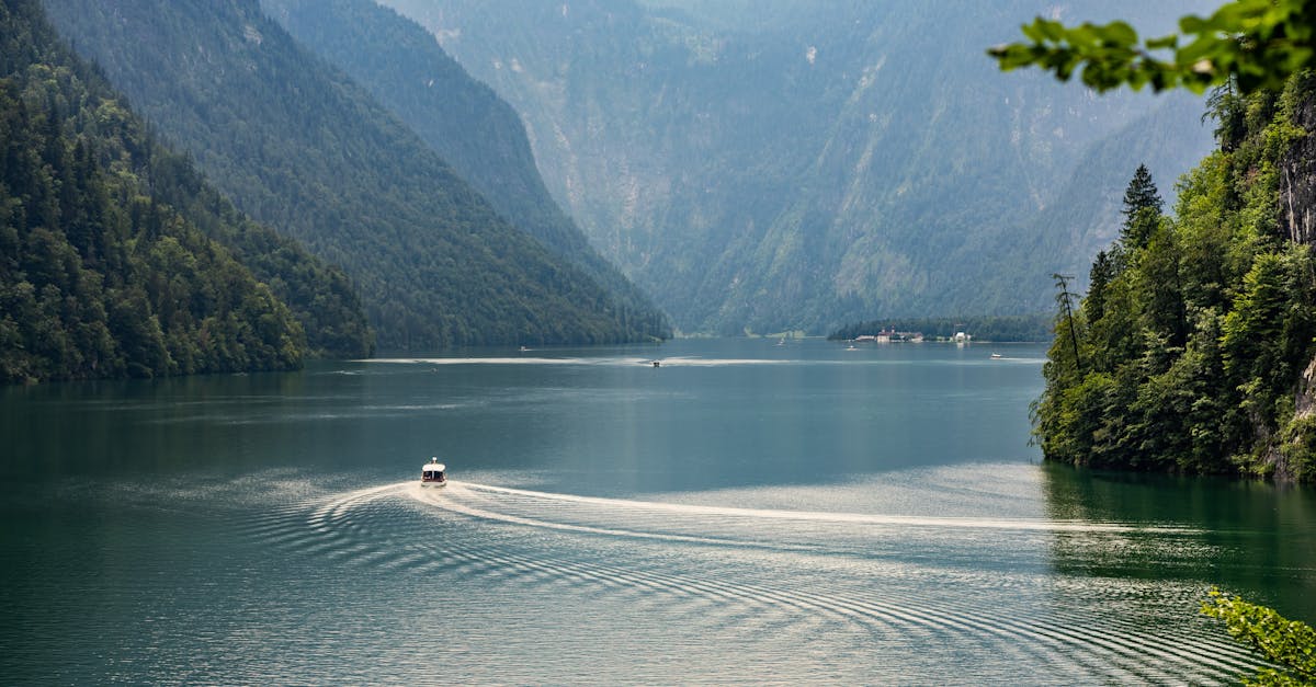 Tranquil scene of a boat on an alpine lake surrounded by lush mountains in Bavaria.