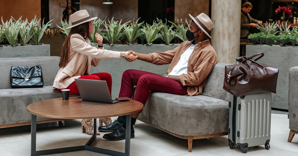 Two fashionable individuals shaking hands in a hotel lobby, showcasing travel and safety.