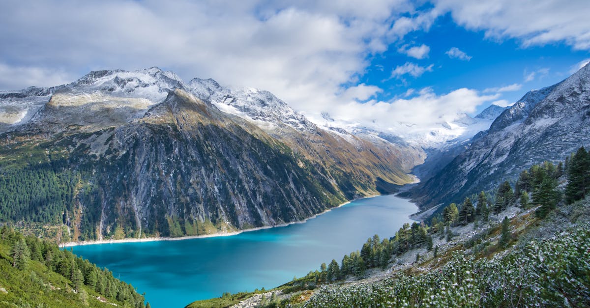 Breathtaking view of turquoise alpine lake surrounded by majestic snow-covered mountains in Tyrol, Austria.