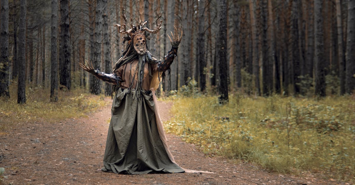 A person wearing an elaborate costume stands in a dense forest, evoking a mysterious and eerie atmosphere.