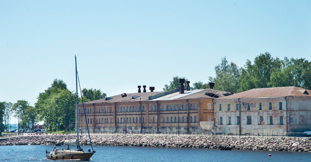 Scenic view of a historic building by the water in Vyborg, Russia, with a sailboat passing by.